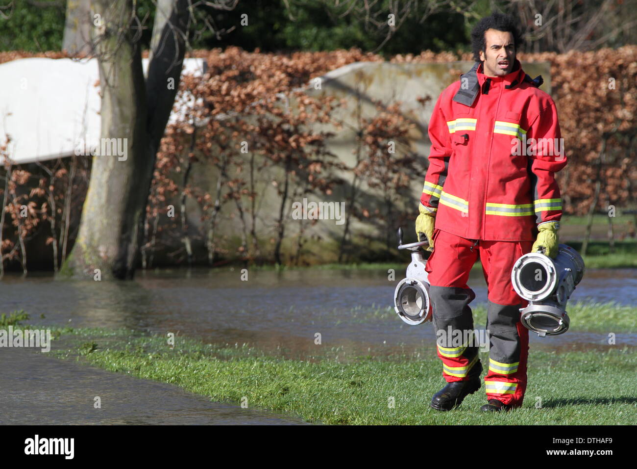 Egham, Surrey, UK. 17. Februar 2014. Ein Feuerwehrmann trägt Grundausstattung durch Hochwasser in Runnymede, in der Nähe von Egham, Surrey.  West Yorkshire Feuer und Rettung Service eingerichtet Pumpen die A308-Windsor-Straße in der Nähe von Runnymede zu löschen. Bildnachweis: John Maxwell-Roberts/Alamy Live-Nachrichten Stockfoto