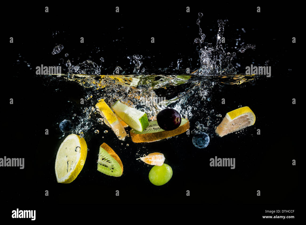 Spritzer frisches Obst auf dem Wasser auf schwarzem Hintergrund Stockfoto