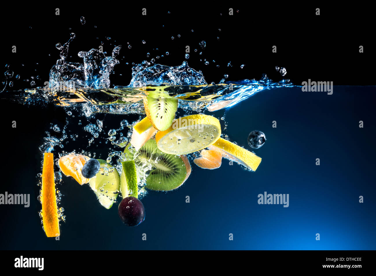 Spritzer frisches Obst auf dem Wasser auf schwarzem Hintergrund Stockfoto