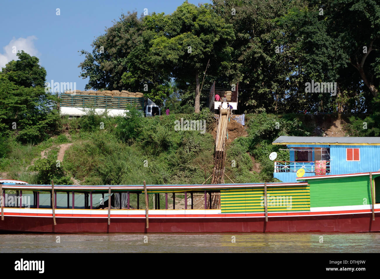 Schiebe-Fracht eine hölzerne Rampe hinunter zu einem Boot auf dem Mekong in Laos. Stockfoto