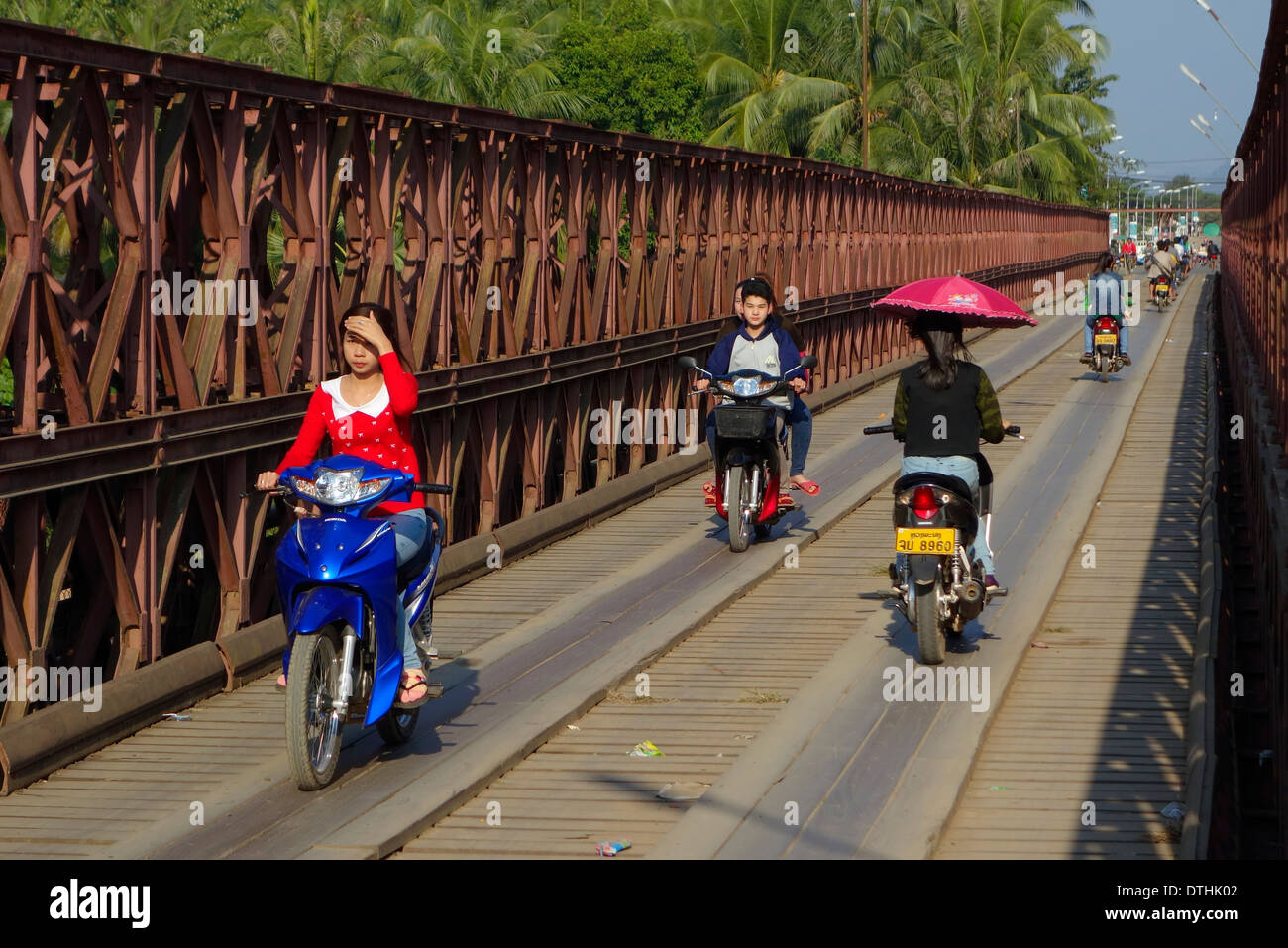 Laoten fahren Motorräder über den Motorrad/Fahrrad Brücke über den Fluss Nam Kahn in Luang Prabang, Laos. Stockfoto