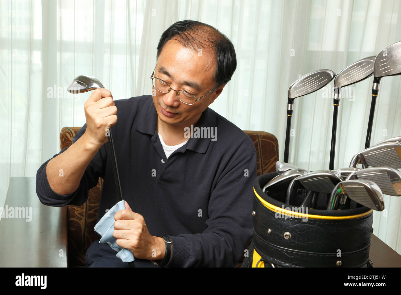 Asiatischer Mann Reinigung zu Hause seinen Golfclub Stockfoto