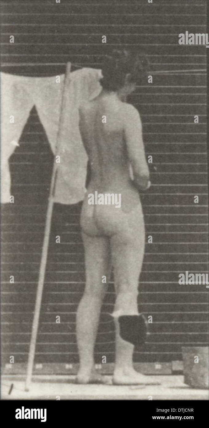 Ein Foto einer nackten Frau, die Kleidung an einer Linie hängt und einen persönlichen, alltäglichen Moment zeigt, der in der Fotografie des frühen 20. Jahrhunderts aufgenommen wurde. Stockfoto