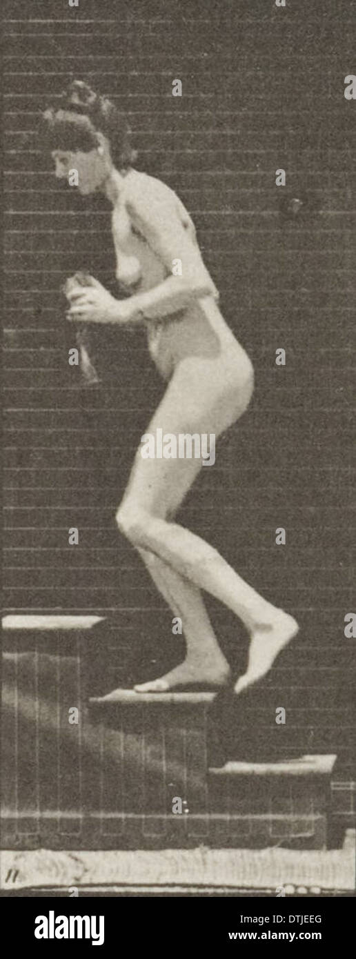 Eine nackte Frau zeigte das Wenden und Aufsteigen von Treppen, während sie einen Krug und einen Kelch in diesem Vintage-Foto hielt. Der Fokus liegt auf ihrer Pose und der Bewegung der Szene. Stockfoto