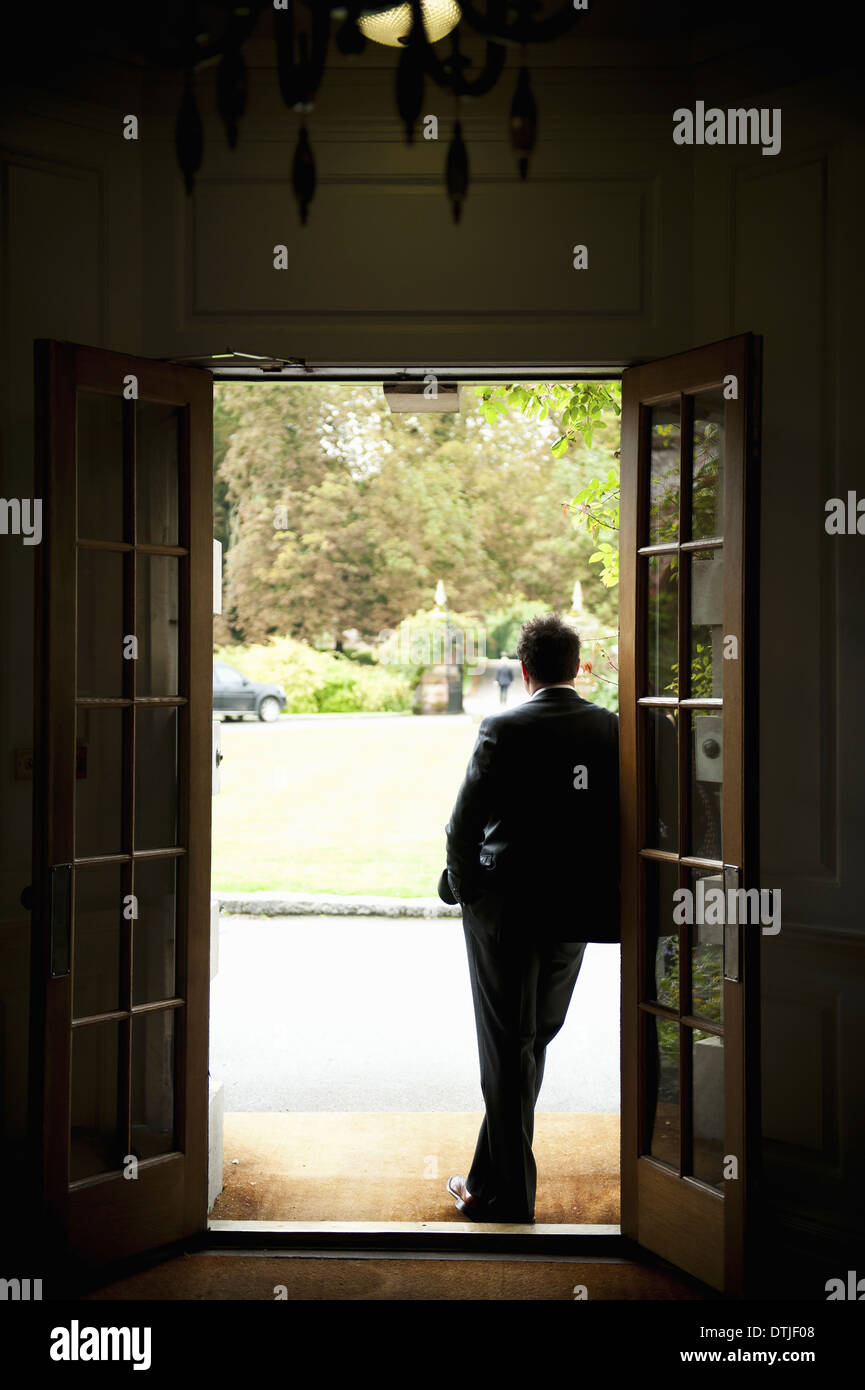 Mann in einem Anzug, lehnte sich gegen die Tür, Blick auf die Open-Air-Betrachtung Stockfoto