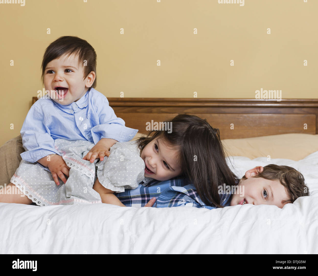 Drei Kinder in einer Familie auf einem großen Bett Pennsylvania USA spielen liegend Stockfoto