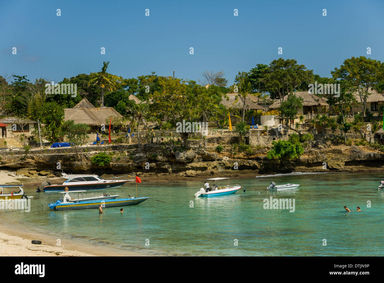 Boote auf dem Wasser und Resort auf der Klippe in der Nähe von dem klaren, blauen Meerwasser an einem sonnigen Tag Nusa Lembongan Thailand Stockfoto