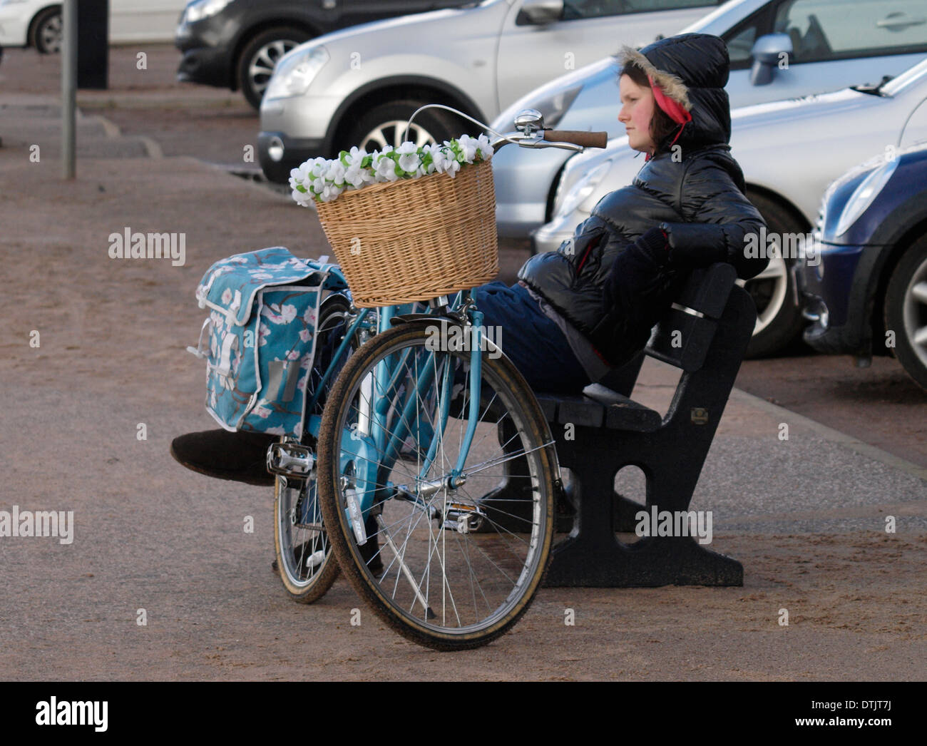Junge Frau saß auf öffentliche Bank mit Fahrrad, Exmouth, Devon, UK Stockfoto