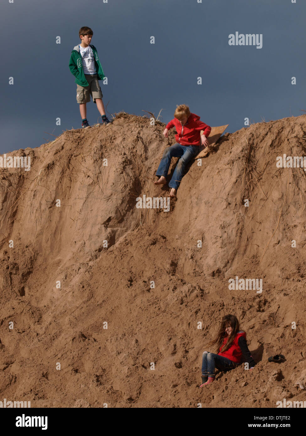 Kind rutscht Sanddünen auf ein altes Stück Holz, Exmouth, Devon, UK Stockfoto