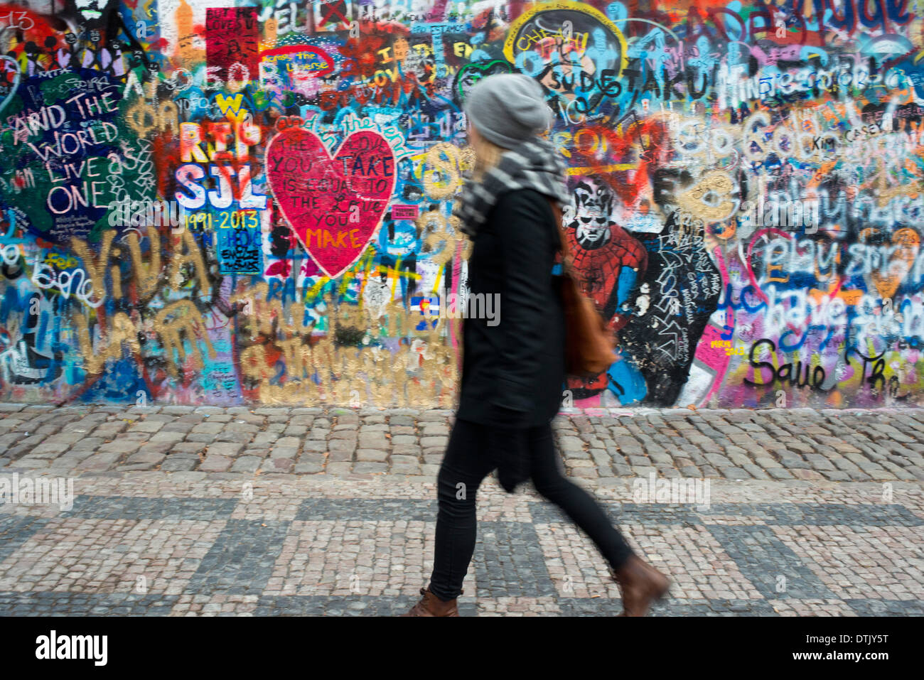 Eine Mädchen geht vorbei an der John-Lennon-Mauer im Zentrum von Prag. Die John-Lennon-Mauer ist eine Mauer, die einst einen Großteil der könnte Stockfoto