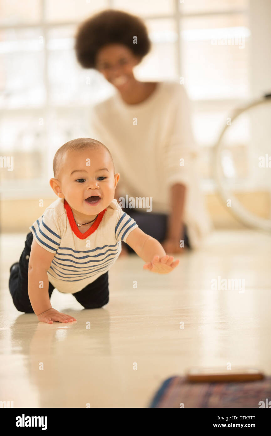Mutter beobachten Baby Boy kriechen am Boden Stockfoto
