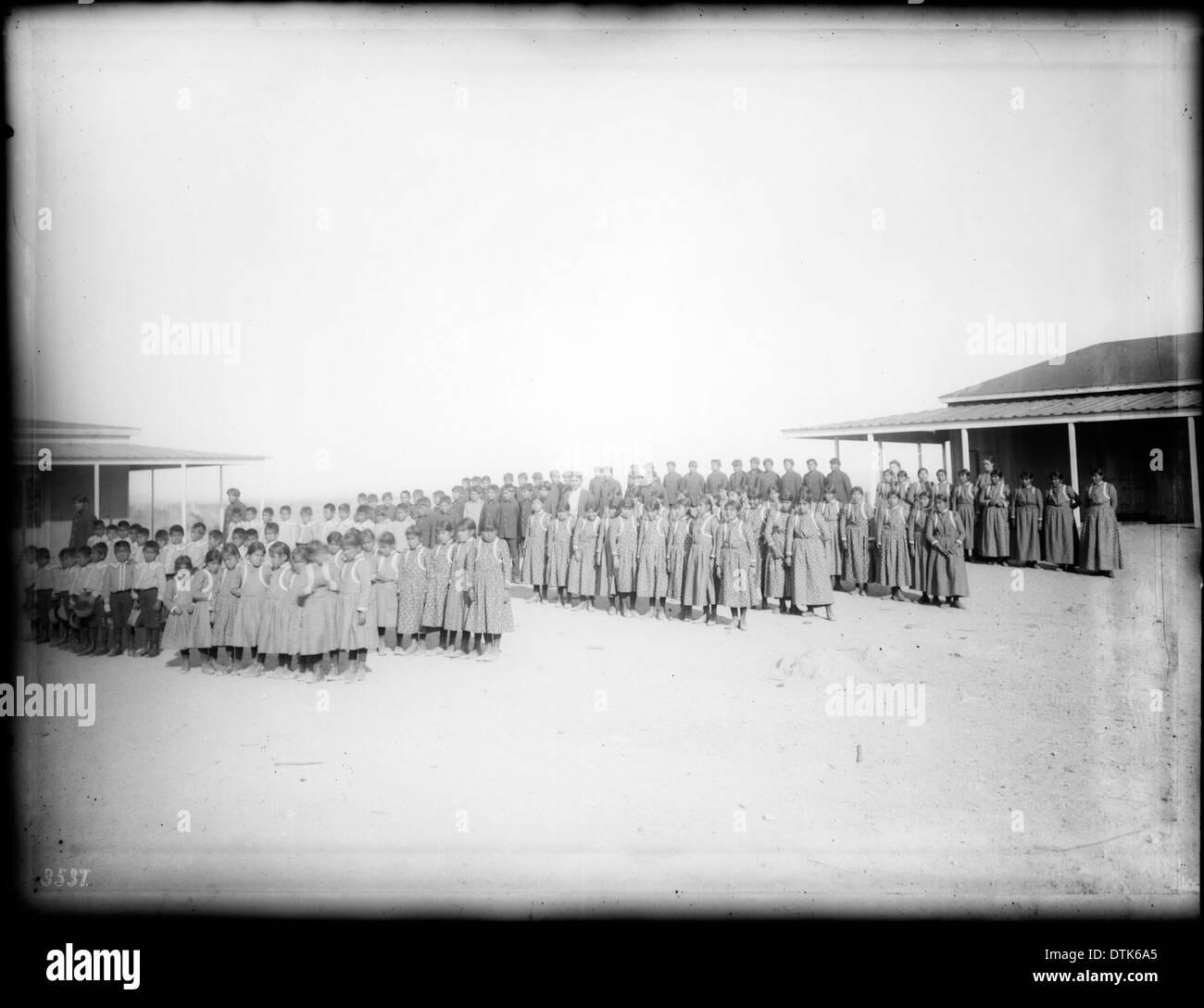 Ein Foto von Jungen und Mädchen der Yuma-Indianer, die zwischen zwei Gebäuden der staatlichen indischen Schule in Yuma posierten, um 1900. Das Bild spiegelt die Rolle der staatlichen Schulen bei der Assimilation der Ureinwohner in dieser Zeit wider. Stockfoto