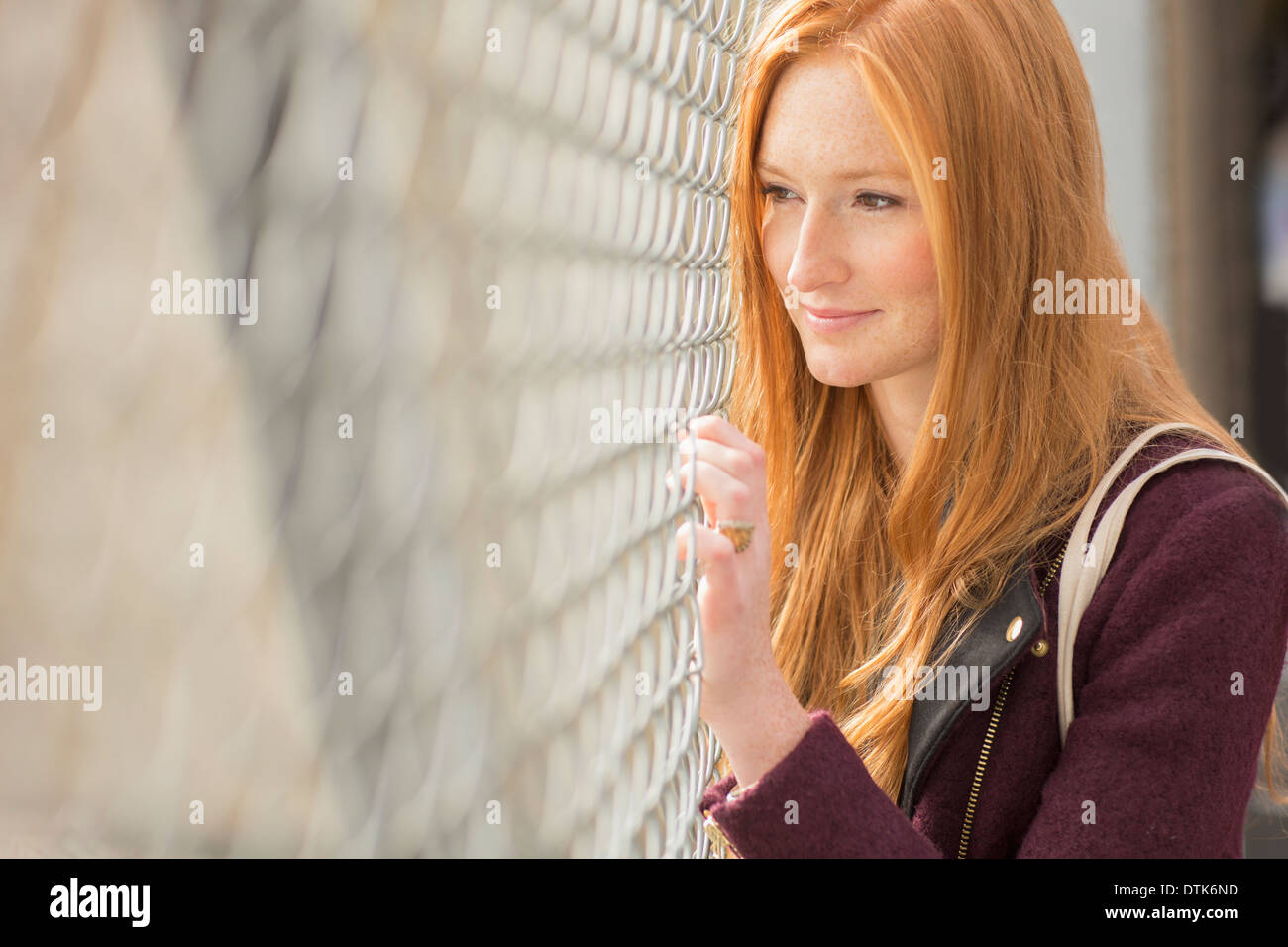 Frau spähte durch Maschendrahtzaun Stockfoto