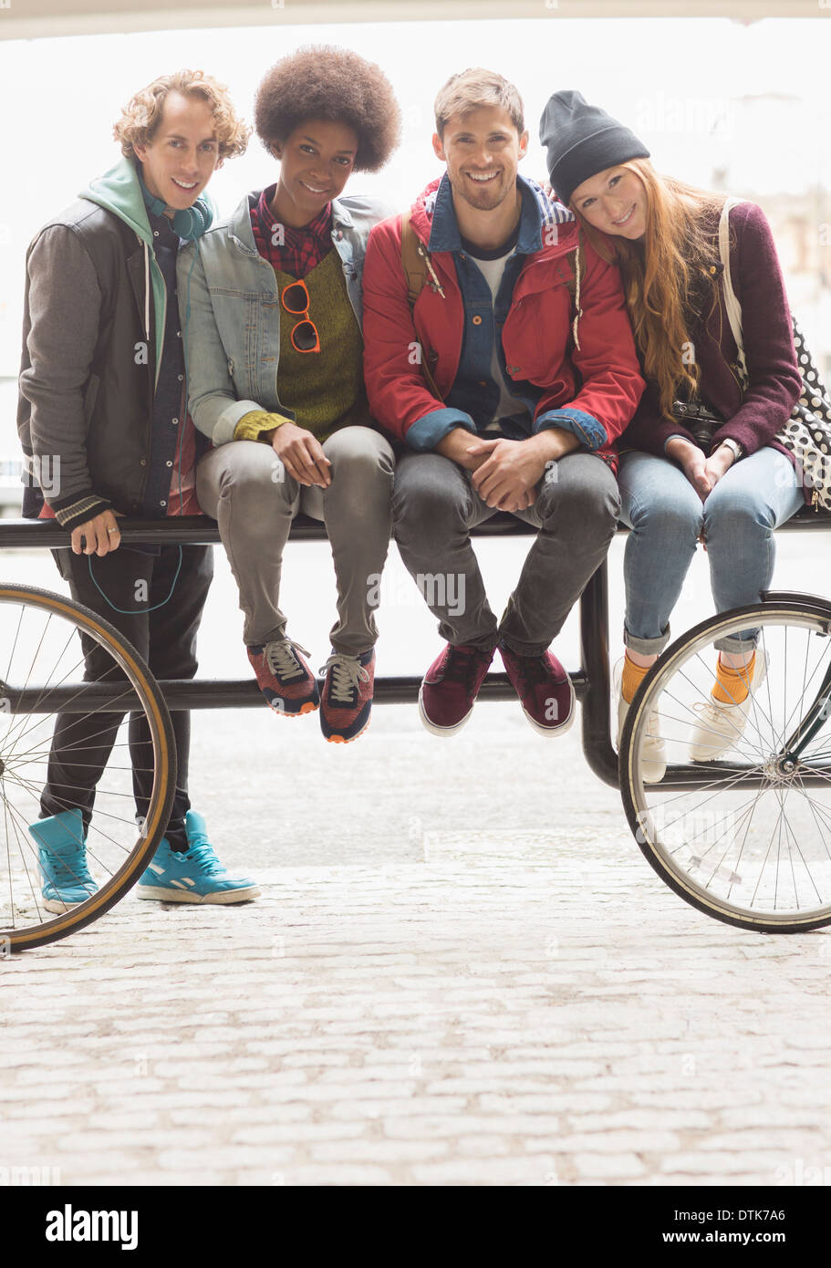 Freunde, die zusammen auf städtischen Fahrradträger lächelnd Stockfoto