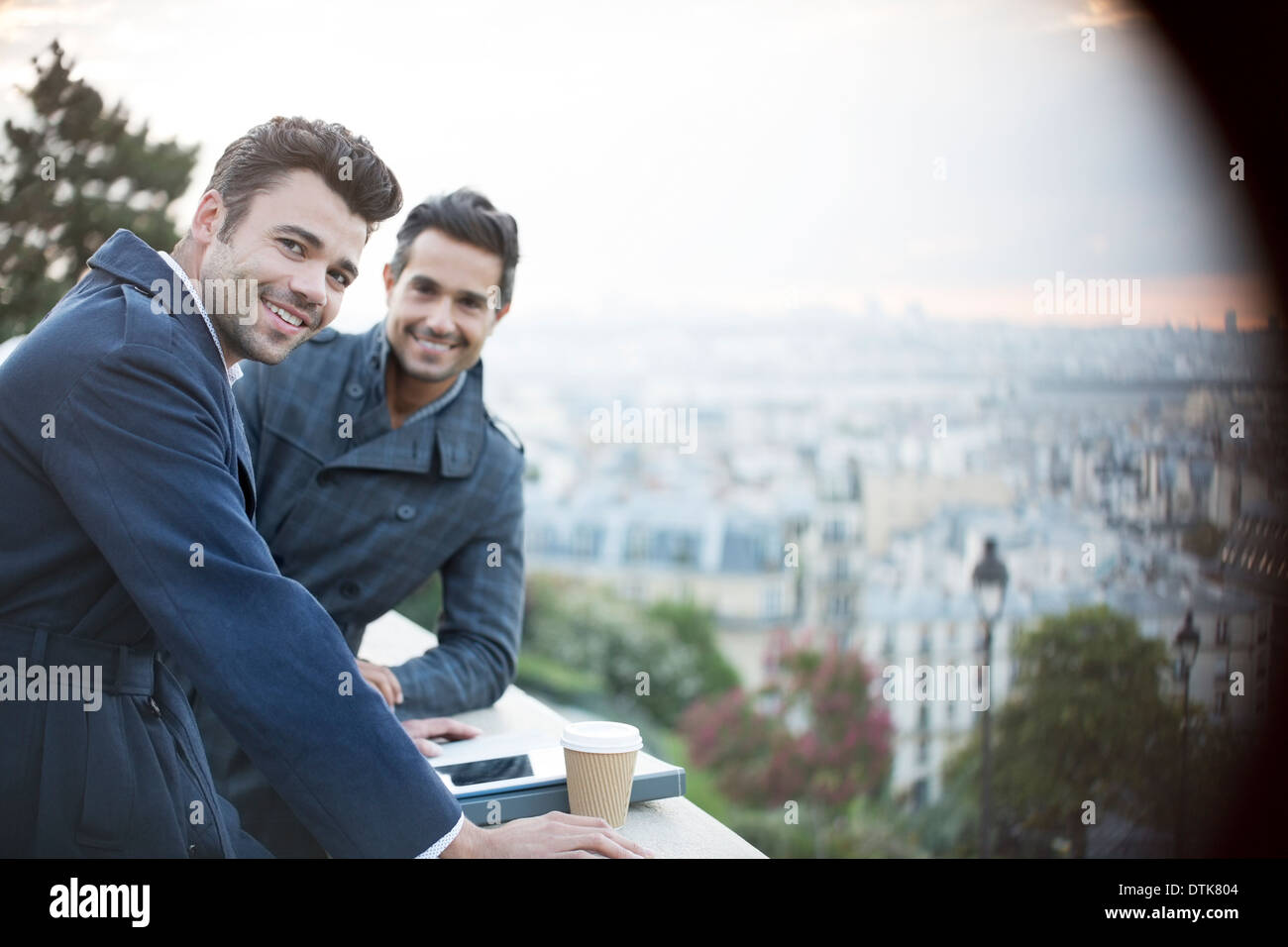 Geschäftsleute, die lächelnd an Geländer mit Blick auf Paris, Frankreich Stockfoto