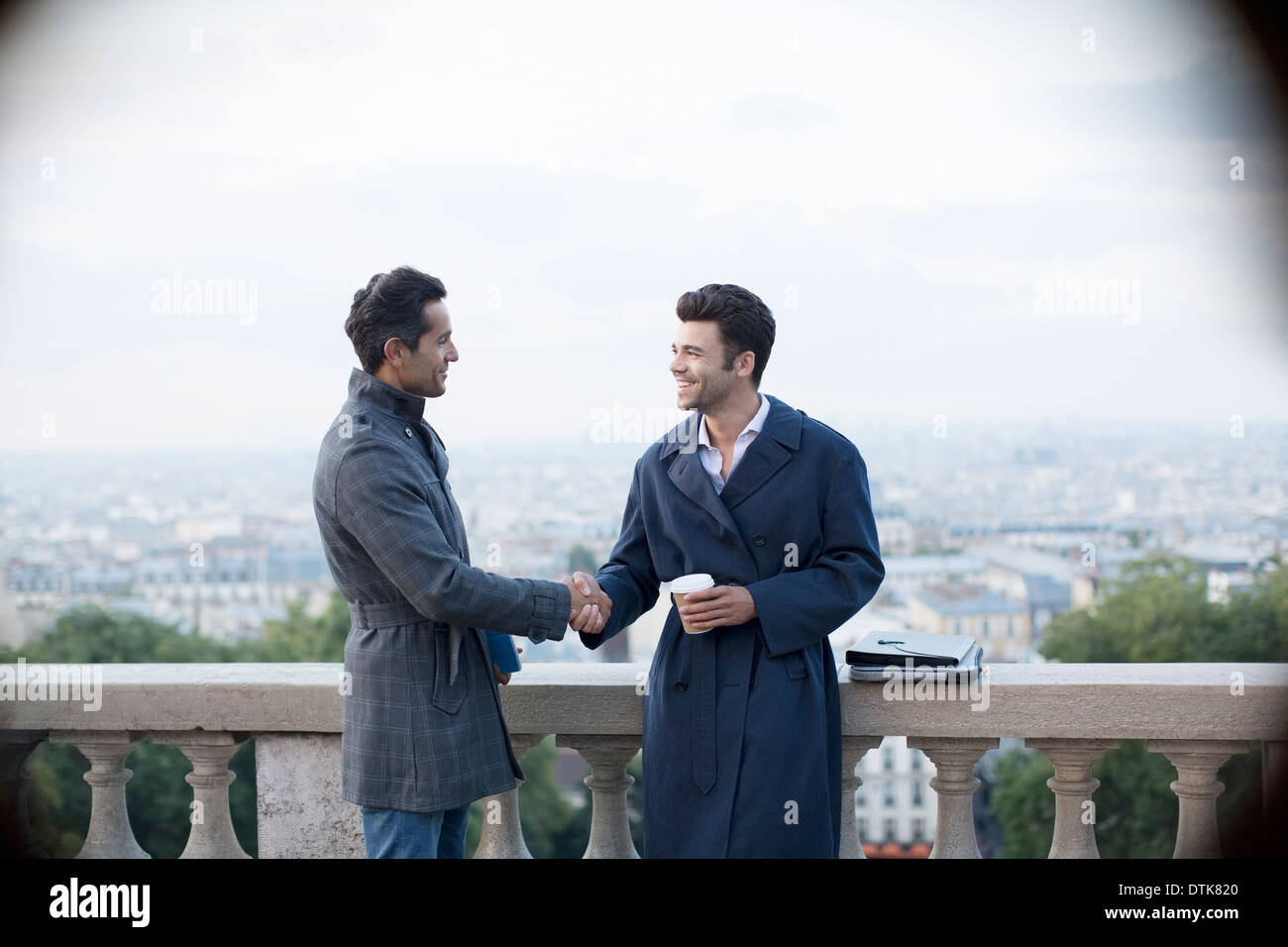 Geschäftsleute Händeschütteln am Geländer mit Blick auf Paris, Frankreich Stockfoto