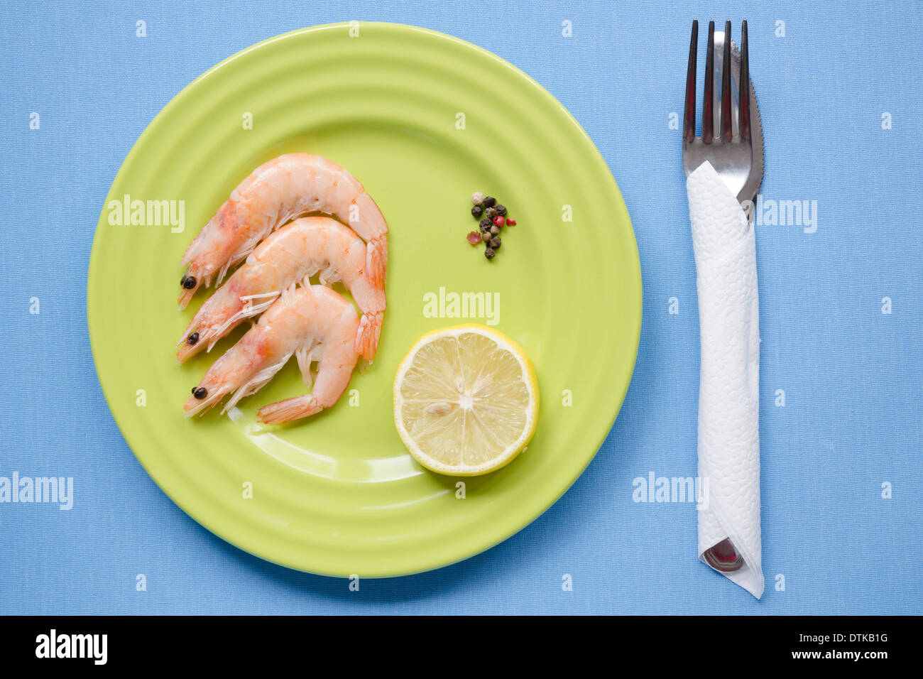 Garnelen-Teil auf grüne Platte mit Zitronenscheibe auf Blaue Tischdecke Stockfoto