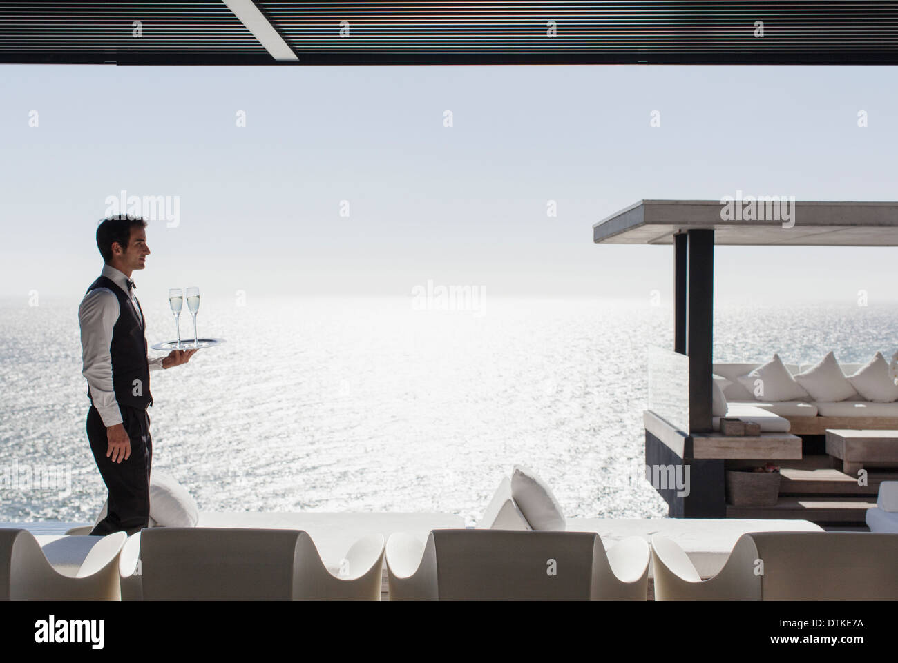 Kellner servieren Champagner im Cabana mit Blick auf Meer Stockfoto