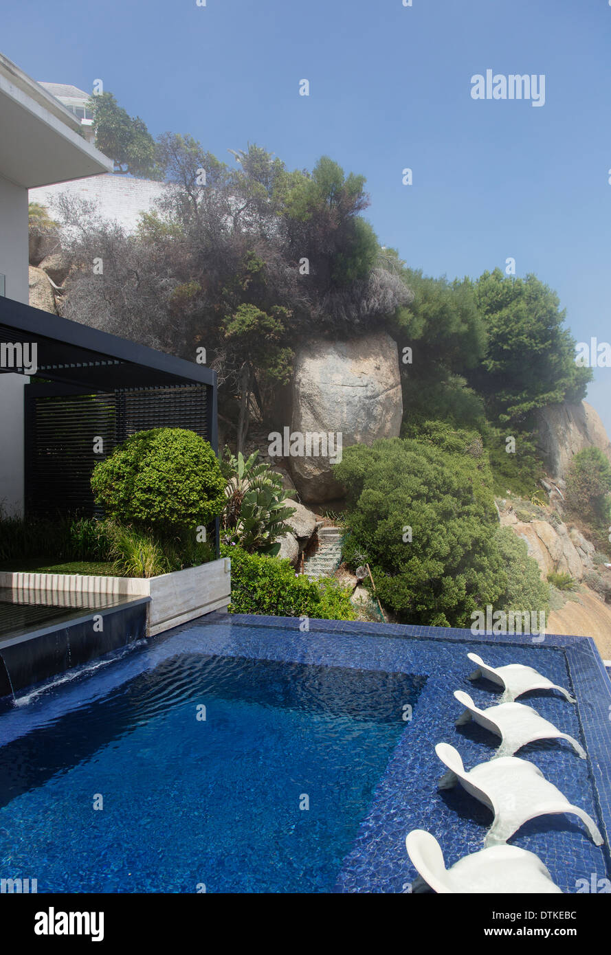 Gartenmöbel im Infinity-Pool mit Blick auf Meer Stockfoto