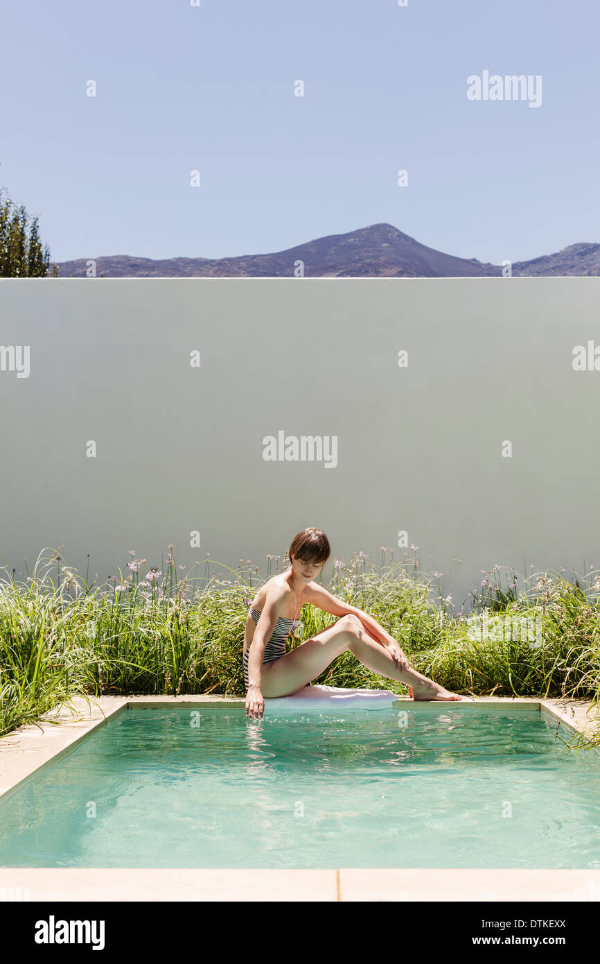 Frau sitzt am Rand des Luxus-Schwimmbad Stockfoto