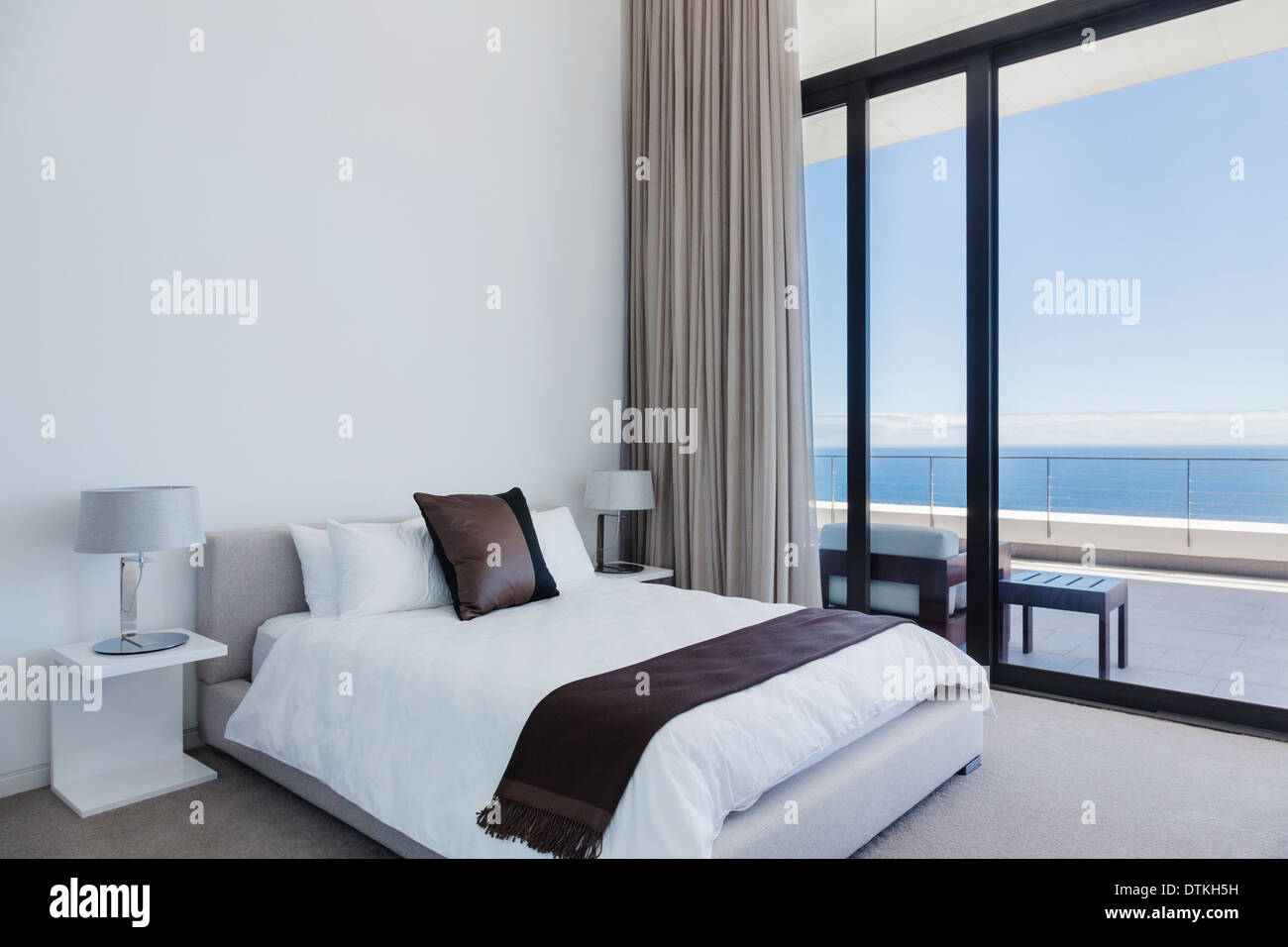 Bett und Lampen in modernen Schlafzimmer mit Blick auf Meer Stockfoto