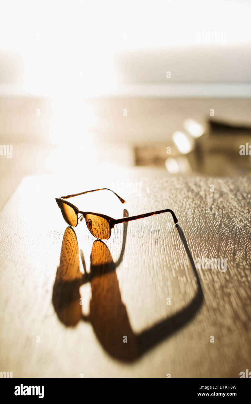 Sonnenbrille wirft Schatten auf Tisch Stockfoto