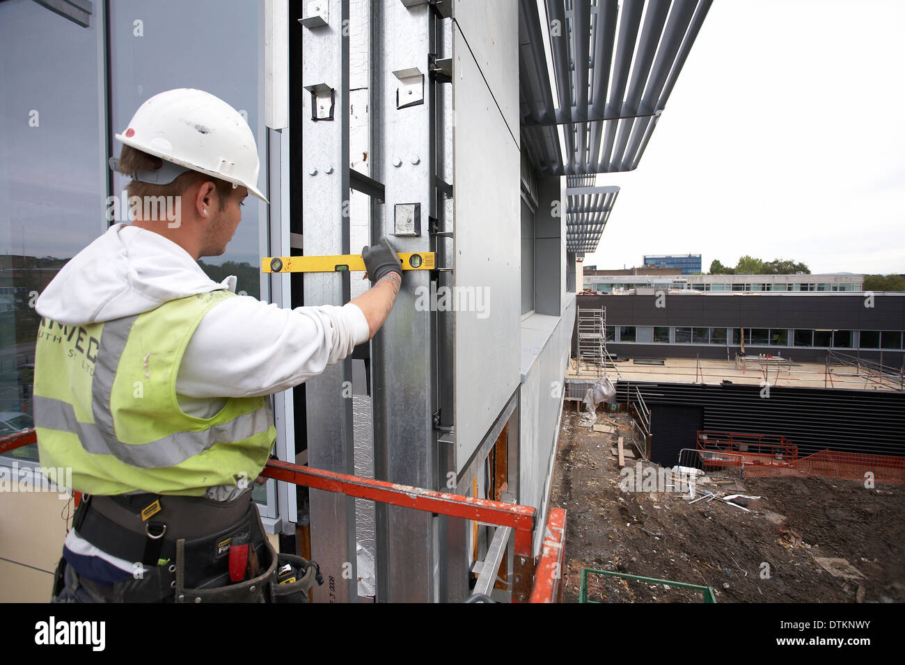 Arbeiter auf einer Hubarbeitsbühne Verkleidung Isolierung und Verkleidung an der Swansea University in South Wales UK zu sichern. Stockfoto