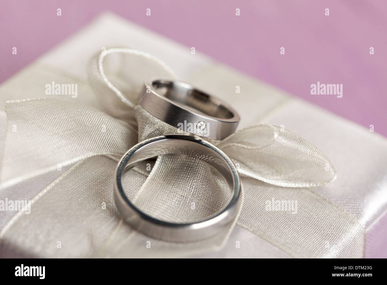 Paar Trauringe auf Geschenk-Box mit silbernen Bogen Stockfoto