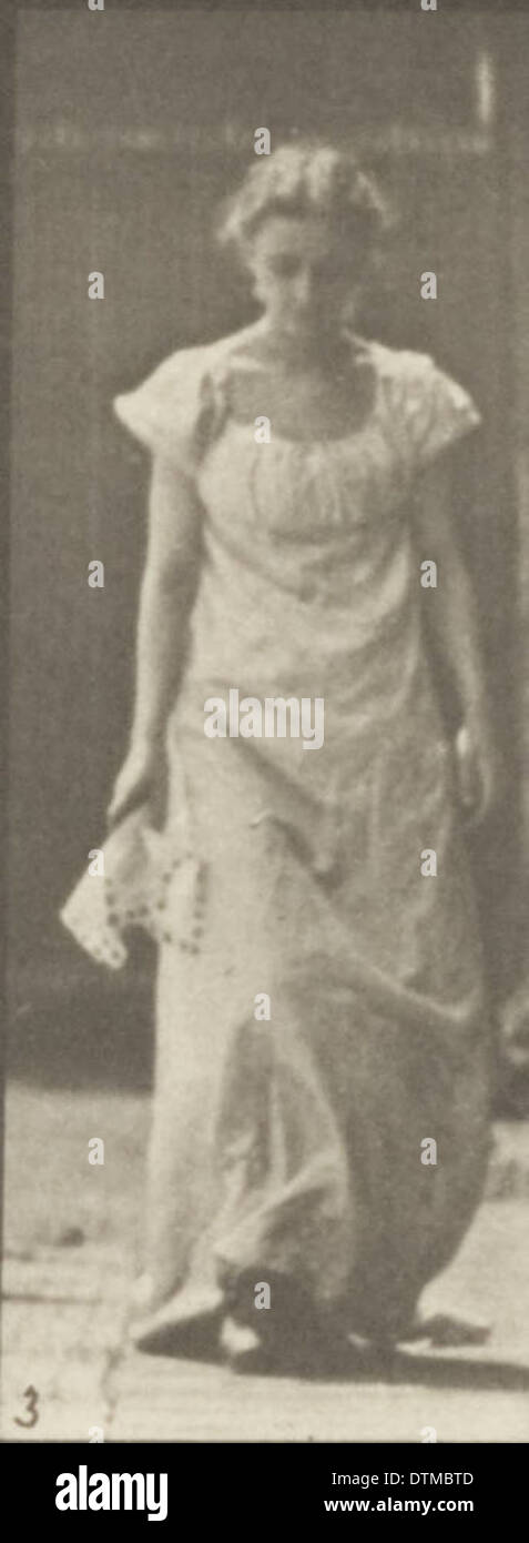 Das Foto zeigt eine Frau in einem langen Kleid, die sich beugt und ein Taschentuch hebt. Das Bild spiegelt Vintage-Mode und das Hausleben aus einer vergangenen Zeit wider. Stockfoto