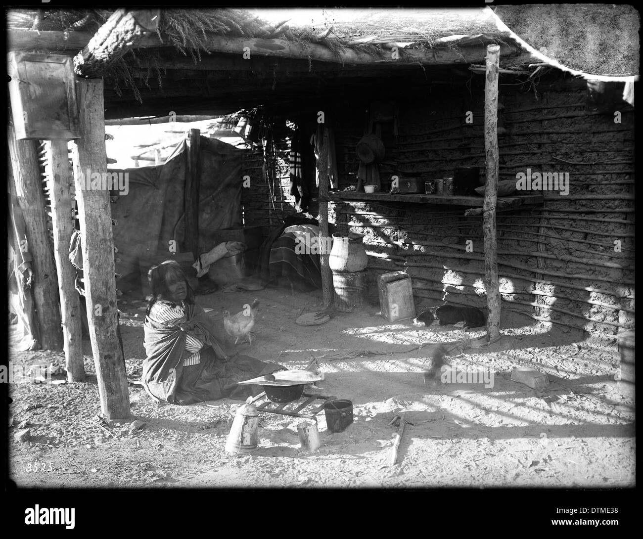 Ein historisches Foto einer Yuma-Indianerin, die im Schatten ihres ramada in der Nähe ihres Kochfeuers sitzt, aufgenommen um 1900. Das Bild zeigt das traditionelle Leben der Ureinwohner Amerikas im frühen 20. Jahrhundert. Stockfoto