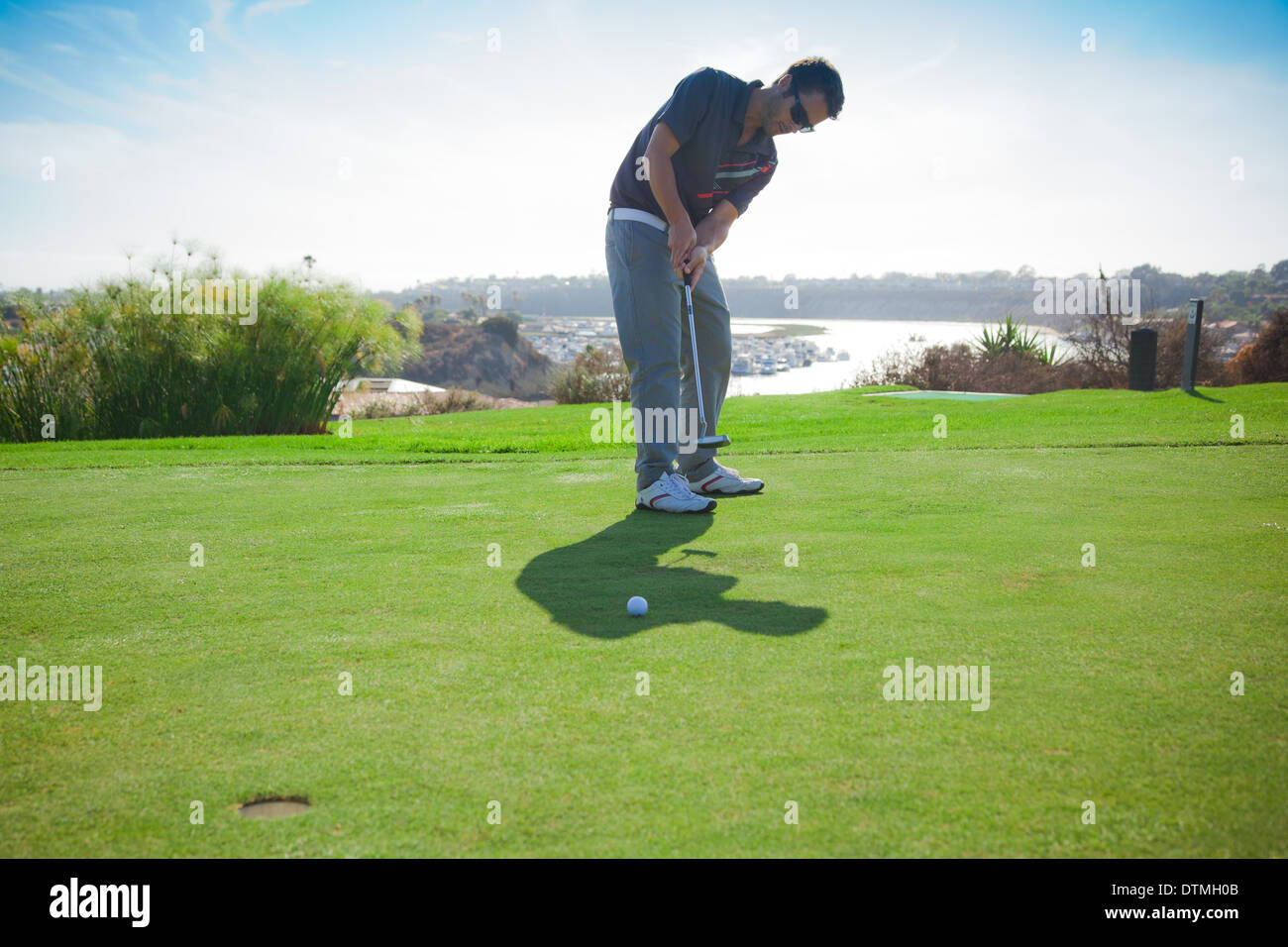 30 Jahre alten Mann Putts auf dem Grün für ein Birdie auf dem Golfplatz Stockfoto