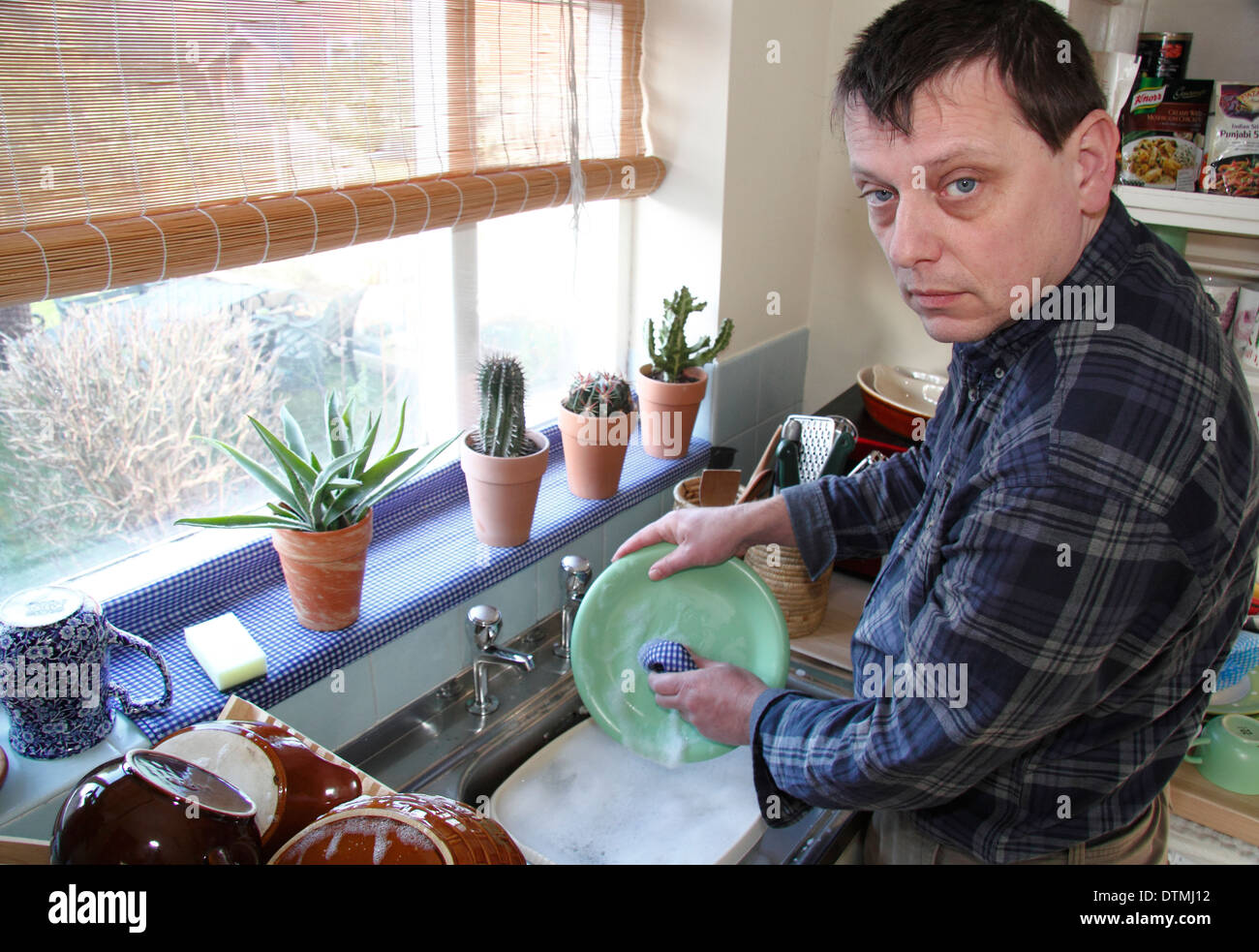 Mann geschirr Töpfe mit wenig Begeisterung an einer Spüle zu Hause, England, Großbritannien Stockfoto