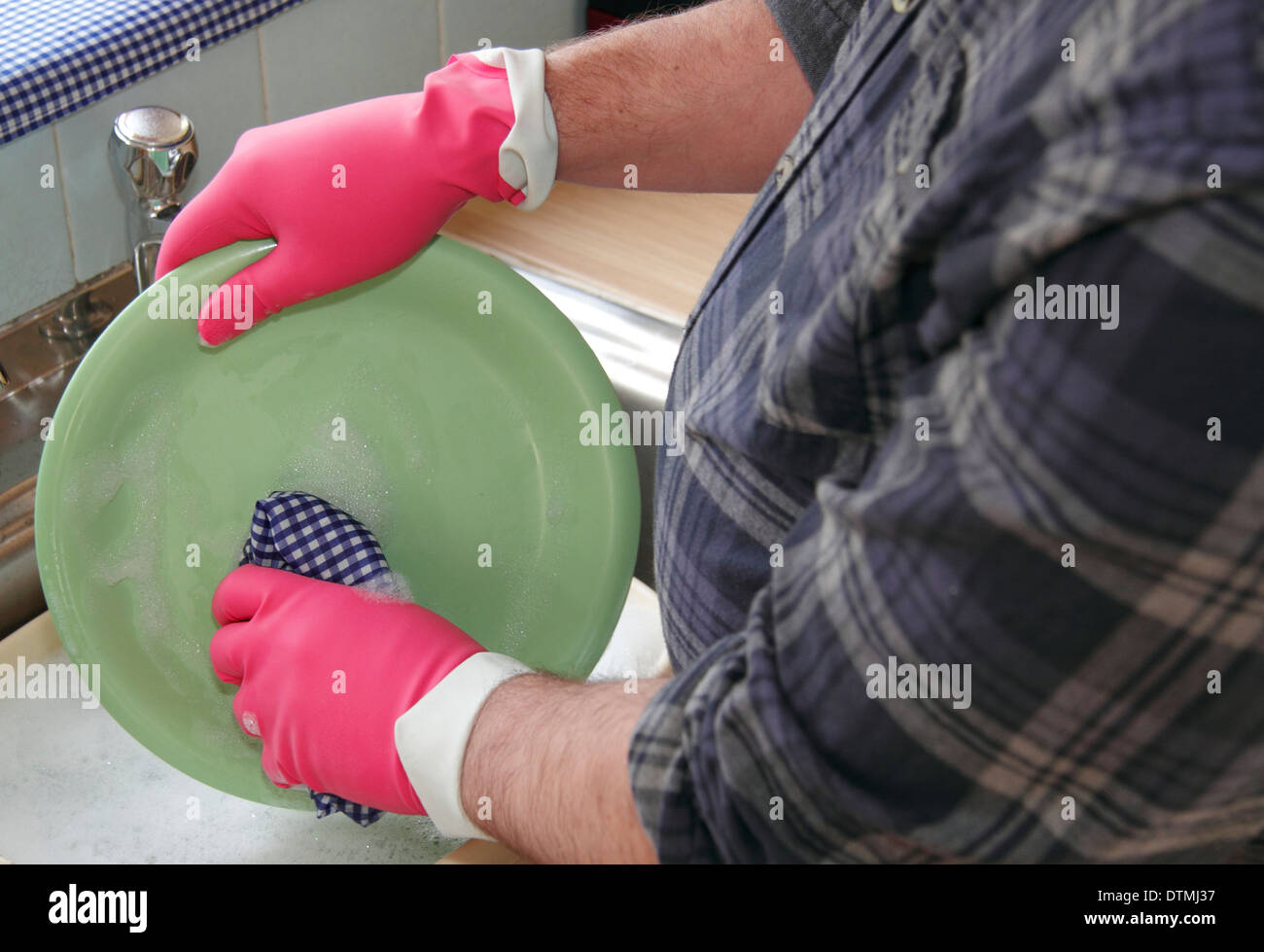 Mann waschen Töpfe/Teller rosa Gummihandschuhen bei einer Küchenspüle zu Hause, England, UK Stockfoto