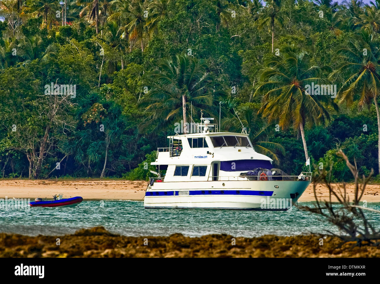 Boot Yacht im Wasser Ozean Meeresstrand mit Palmen und Felsen am Horizont Landschaft tropischen Strand Stockfoto