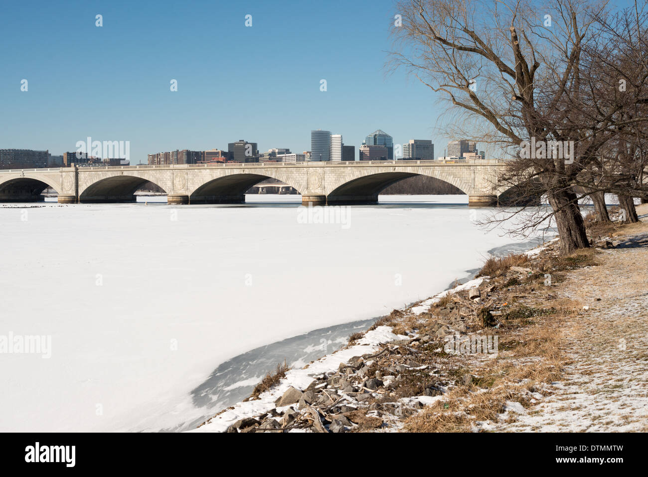 WASHINGTON DC, USA - Arlington Memorial Bridge überspannt eine Fläche von Eis und Schnee - Potomac von Washington D.C. in Arlington, Virginia, mit den Gebäuden von Rosslyn in der Ferne sichtbar. Die Potomac in Washington DC ausgeführt wird eingefroren und mit einer Schicht von Schnee bedeckt. Die Region hat einen ungewöhnlich kalten Winter erlebt, mit anhaltend niedrigen Temperaturen. Stockfoto