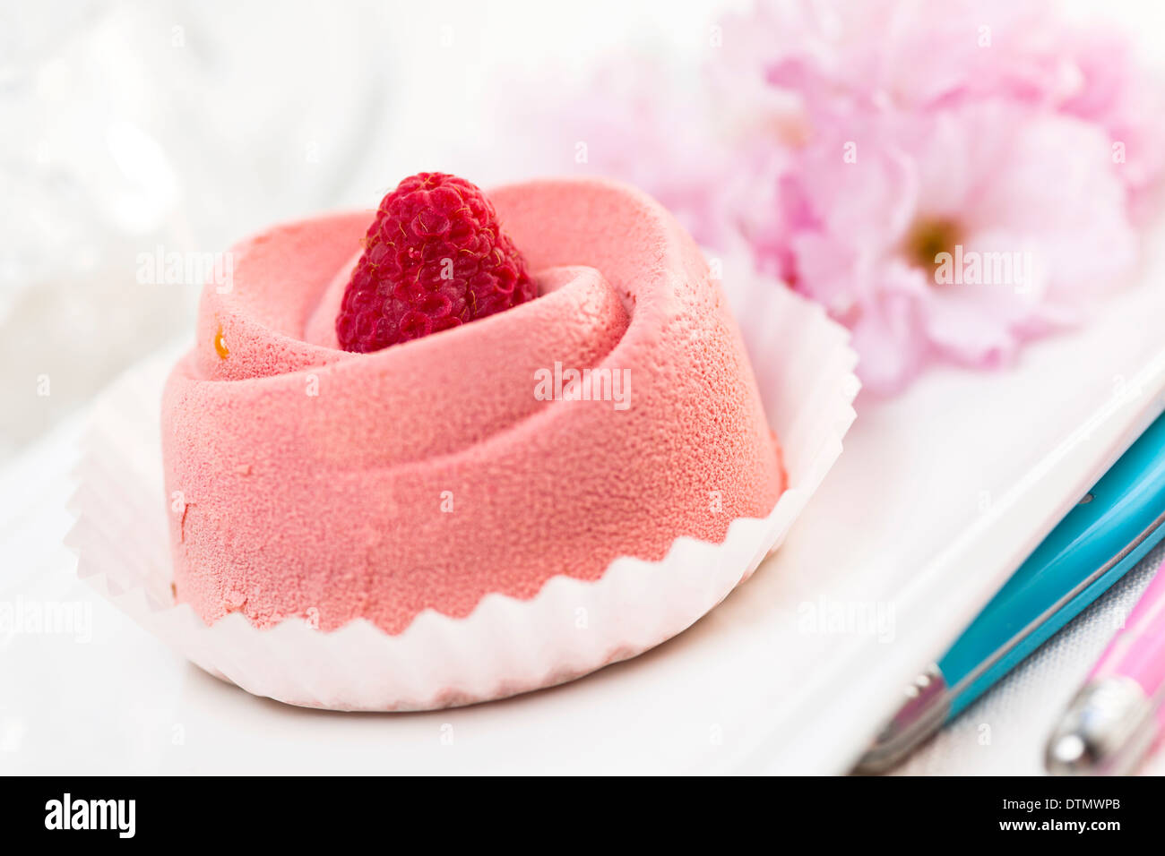 Nahaufnahme von rosa Himbeer Mousse Dessert mit Kirschblüten Stockfoto