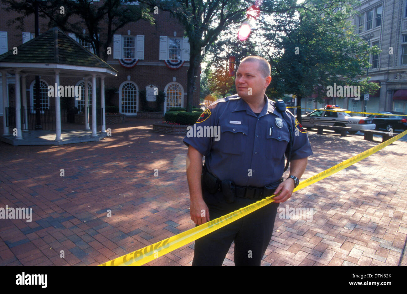 Polizist in Lancaster, Pennsylvania steht hinter gelben Polizei Kordon Band nach einem Banküberfall. Stockfoto