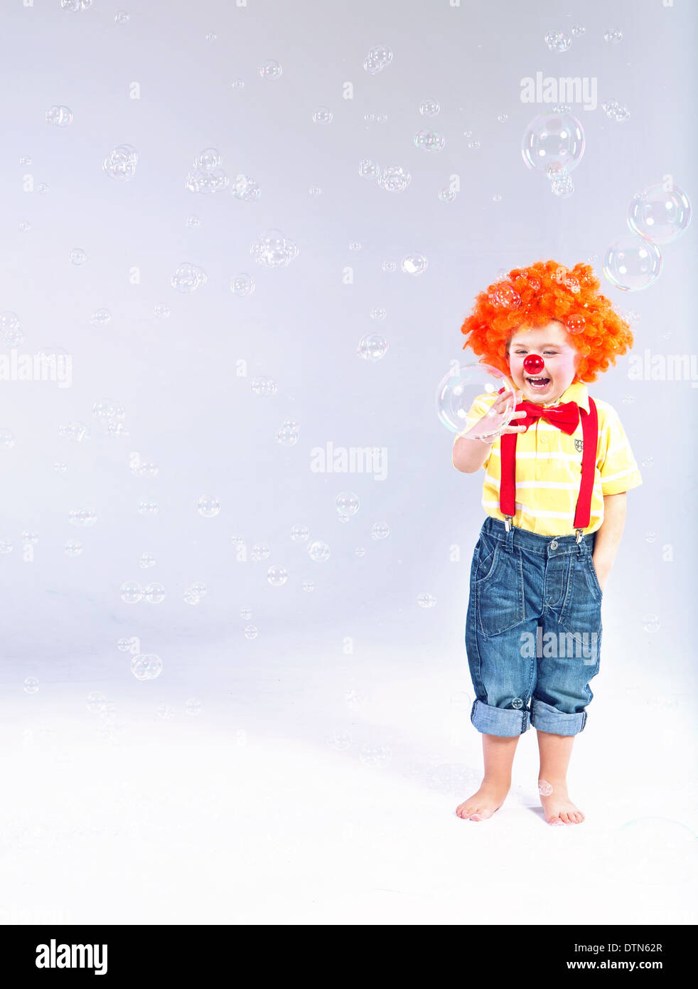 Lustiges Bild des kleinen Clowns machen große Seifenblasen Stockfoto