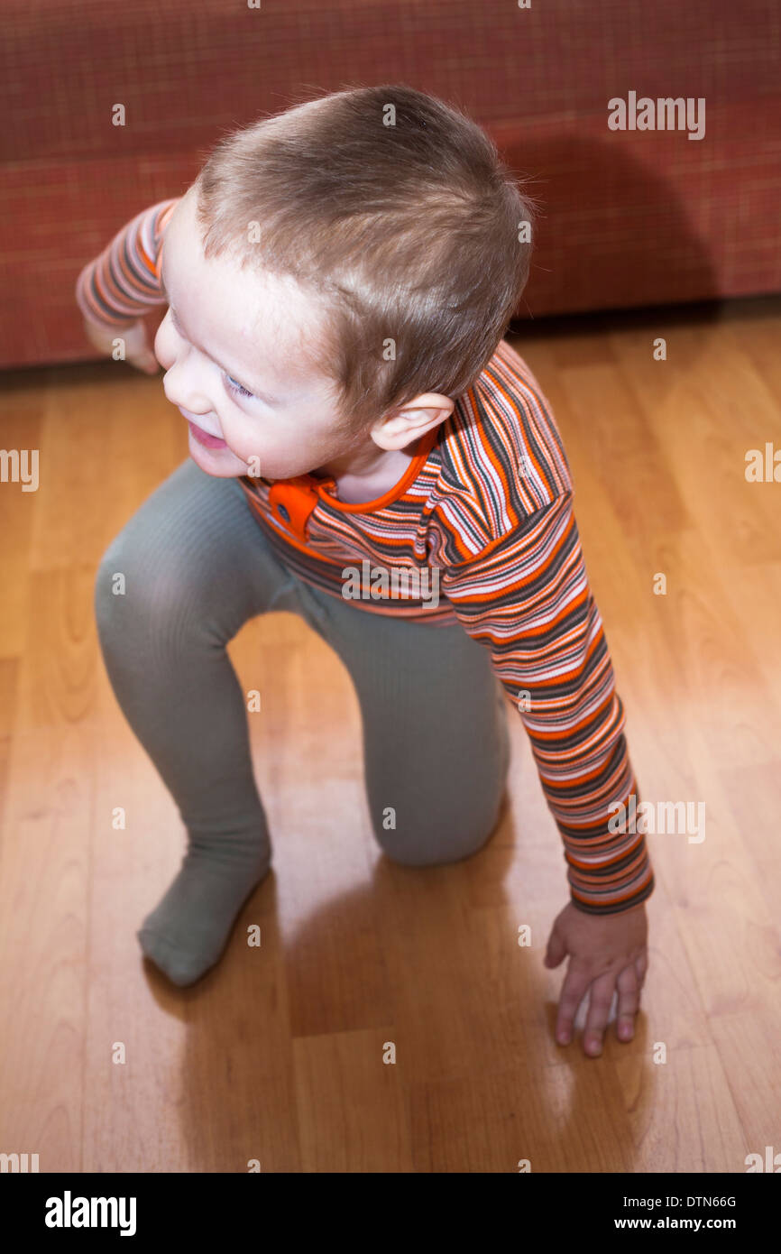 Glücklich spielendes Kind Junge kniend auf dem Boden. Stockfoto