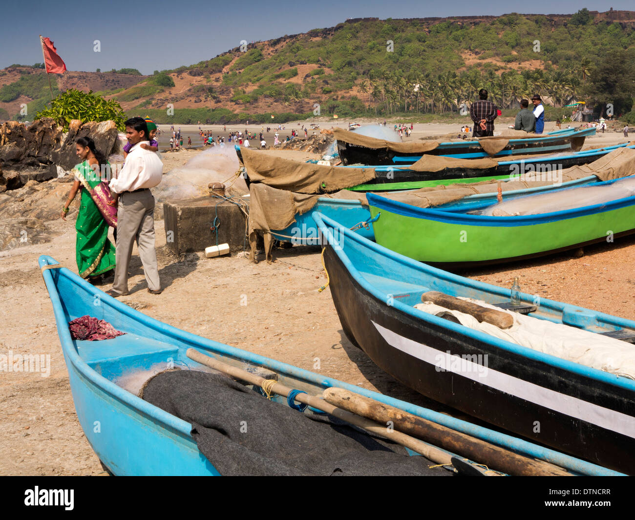 Indien, Goa, Vagator Beach, indische Touristen unter Angelboote/Fischerboote Stockfoto