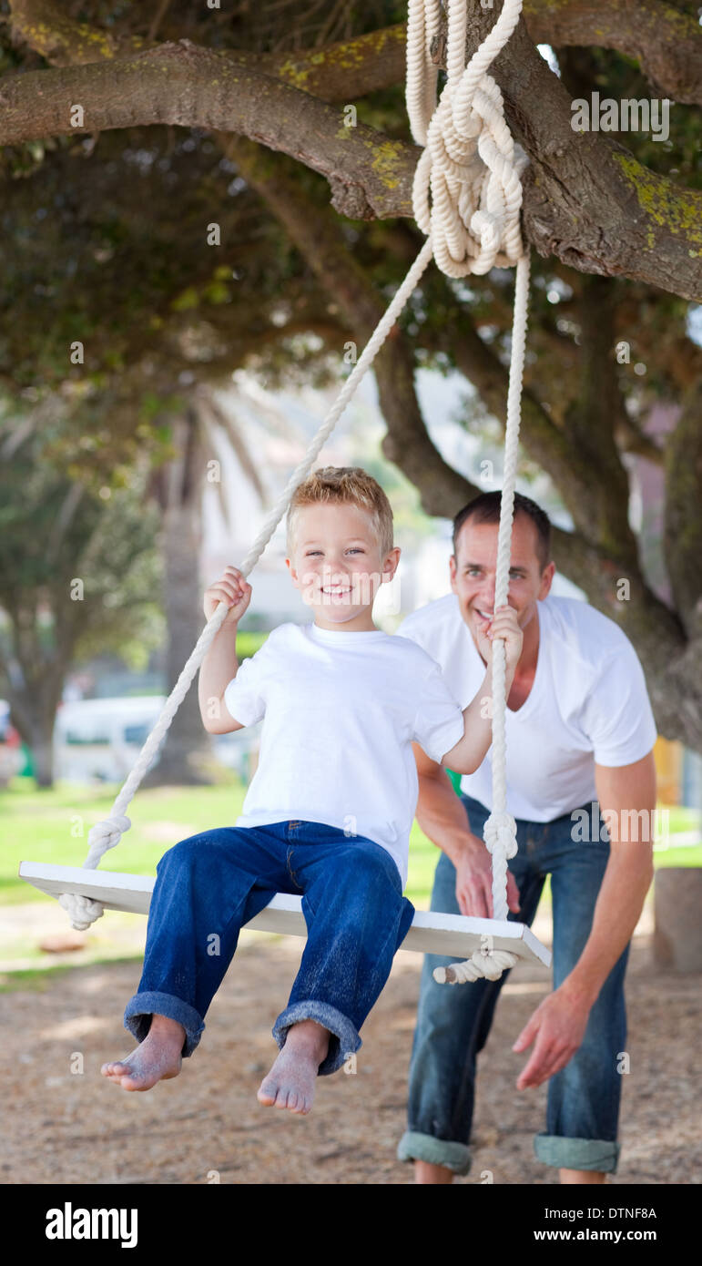 Jolly Vater schob seinen Sohn auf einer Schaukel Stockfoto