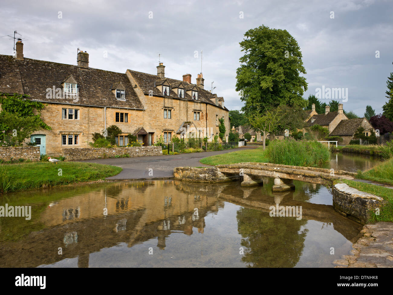 Ferienhäuser und Fußgängerbrücke über den Fluss Auge in den Cotswolds Dorf von Lower Slaughter, Gloucestershire, England. Stockfoto