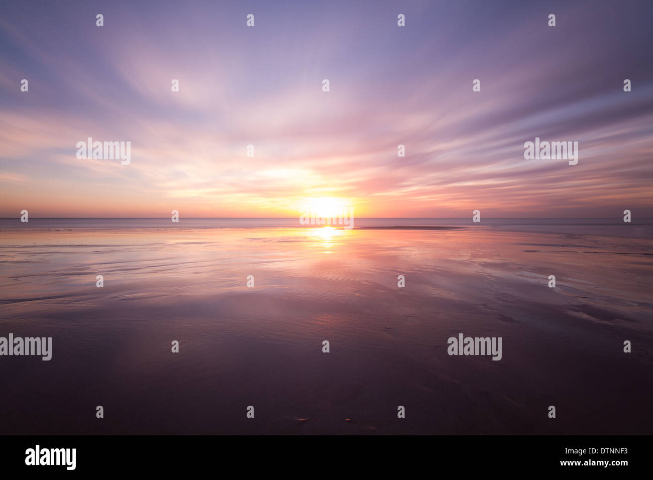 Sonnenuntergang über das Meer und einen nassen Sandstrand reflektieren den Himmel und schöne ruhige entspannende Farben zu schaffen. Stockfoto