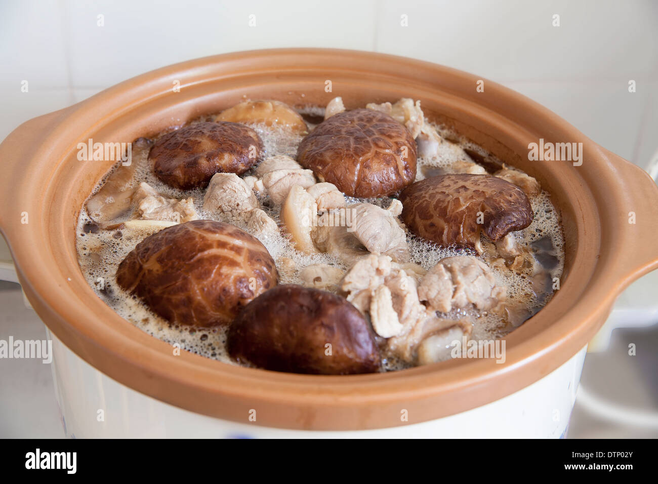 Geschmorte Shiitake schwarzen Pilzen und Schweinefleisch kochen im Slow Cooker Pot Closeup Stockfoto