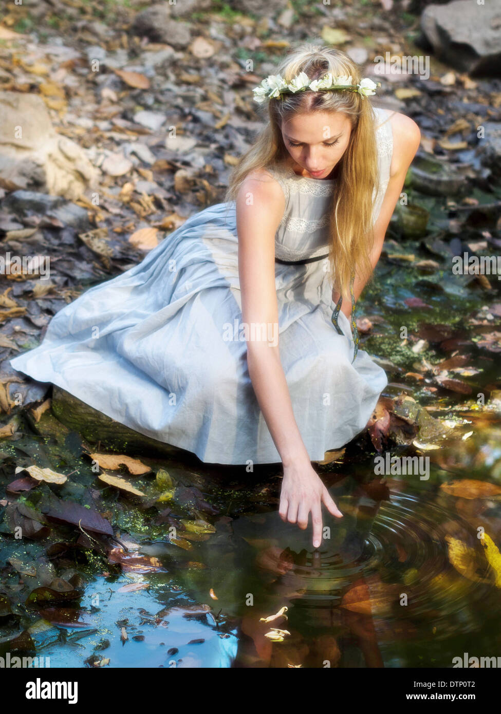 Schönes Märchenprinzessin trägt eine Krone aus Blumen, Wasser Teich sitzen. Stockfoto