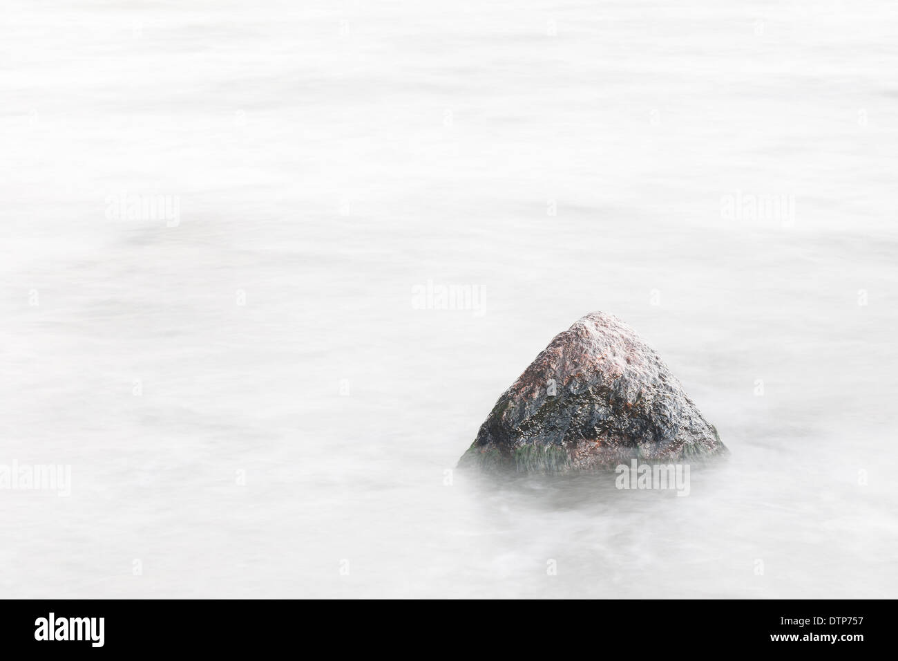 Einzelner Stein oder Fels in einem verschwommenen Meer Stockfoto