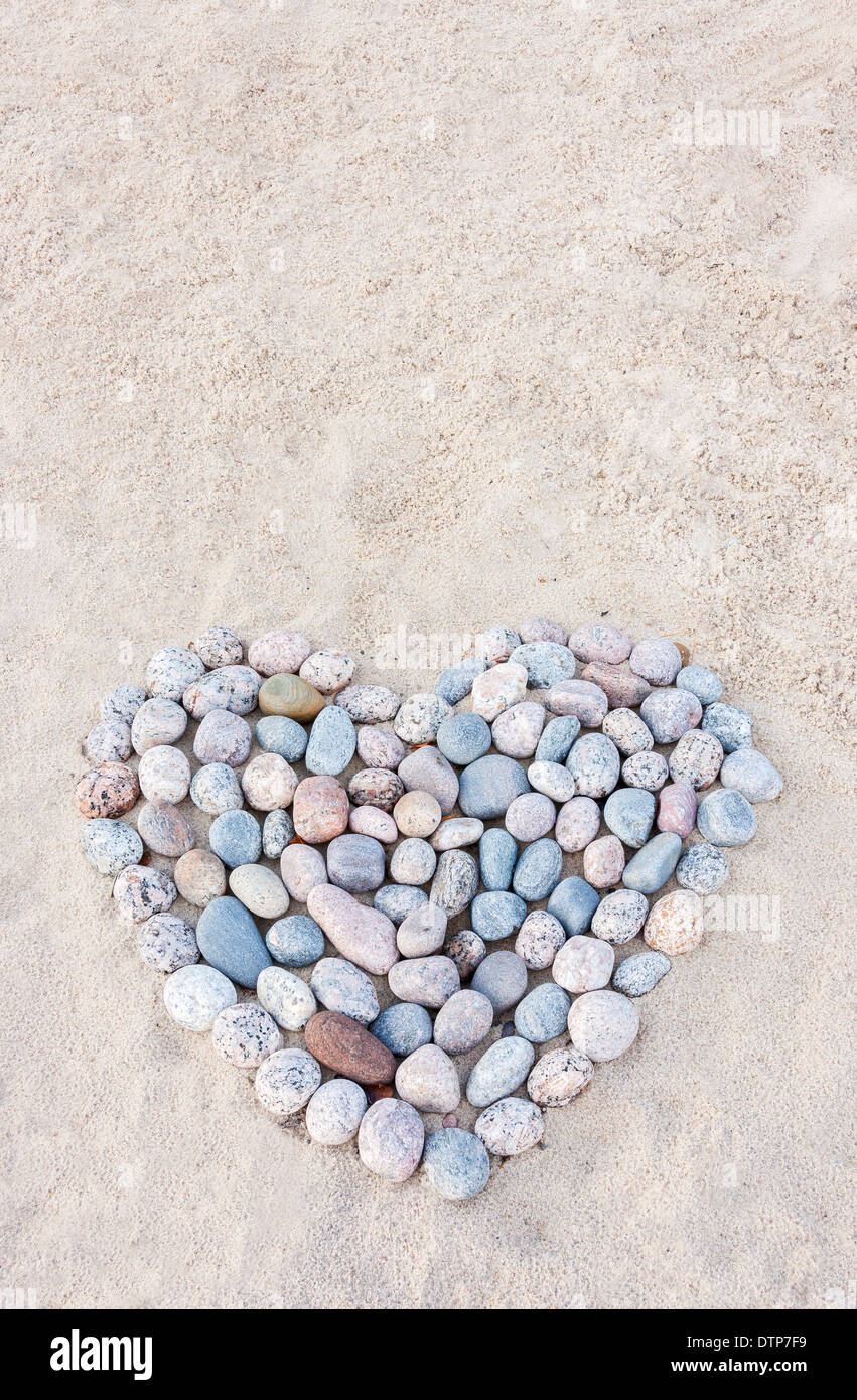 Herz des bunten runden Steinen auf Sand am Strand Stockfoto