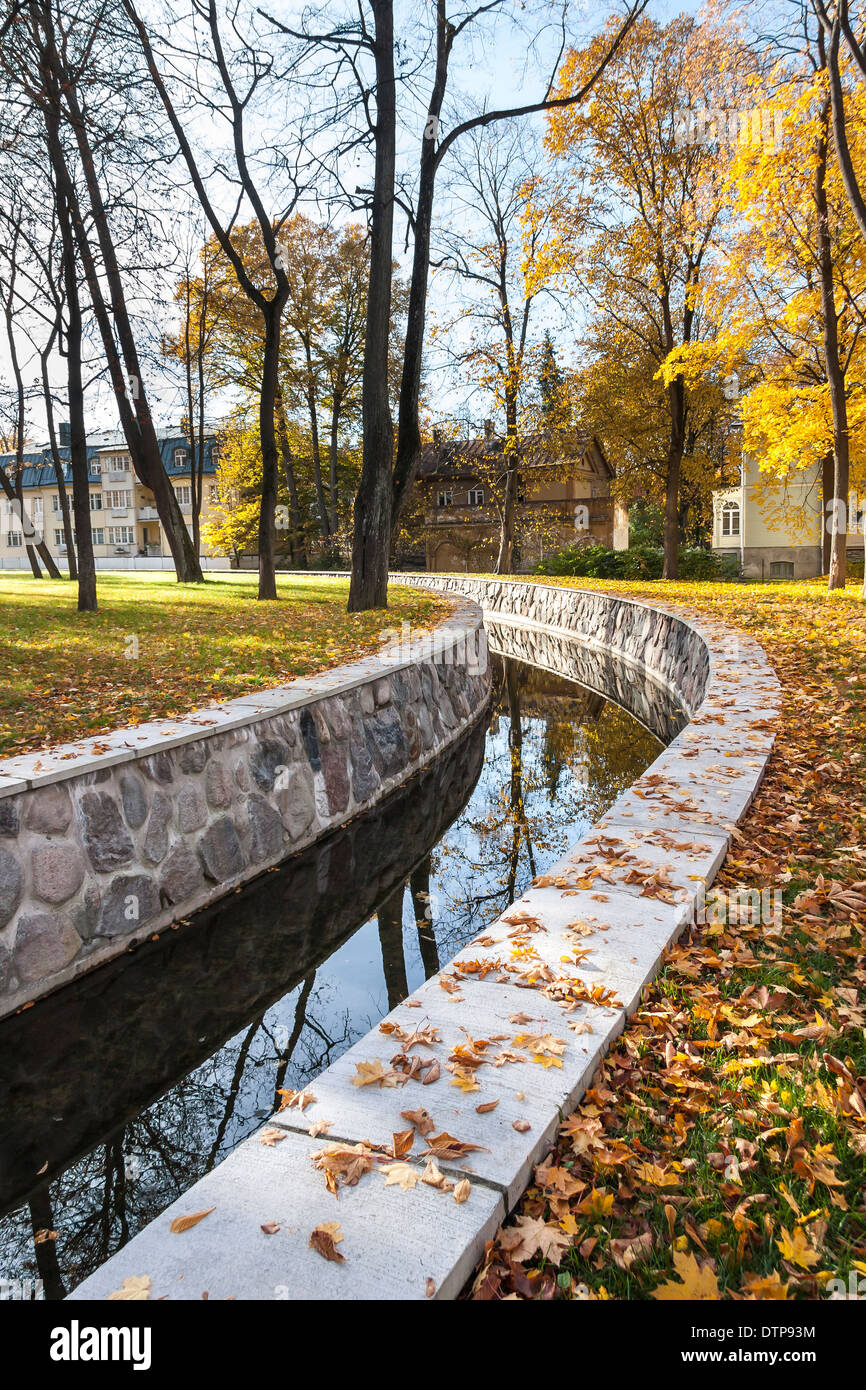 Kanal oder Rohr in einem Park im Herbst, Häuser im Hintergrund Stockfoto