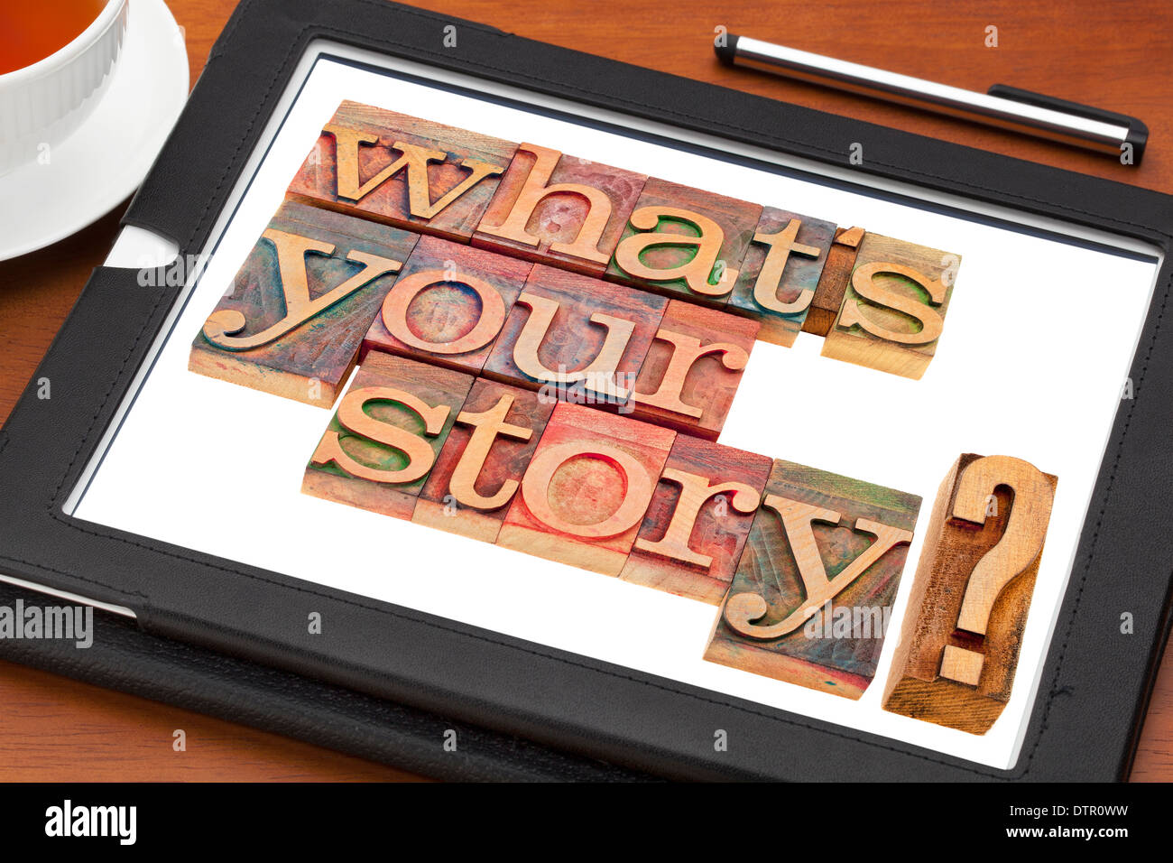Was ist Ihre Geschichte Frage in Vintage Holz Buchdruck Druckstöcken auf einem digitalen Tablet mit einer Tasse Tee Stockfoto
