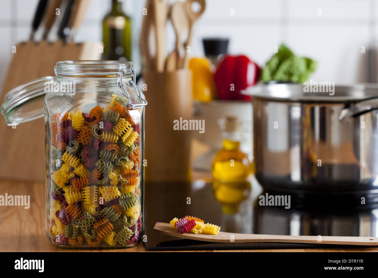 Lagerung Jar mit bunten Nudeln und Kochen Löffel auf Arbeitsplatte mit textfreiraum am rechten Bildbereich Stockfoto